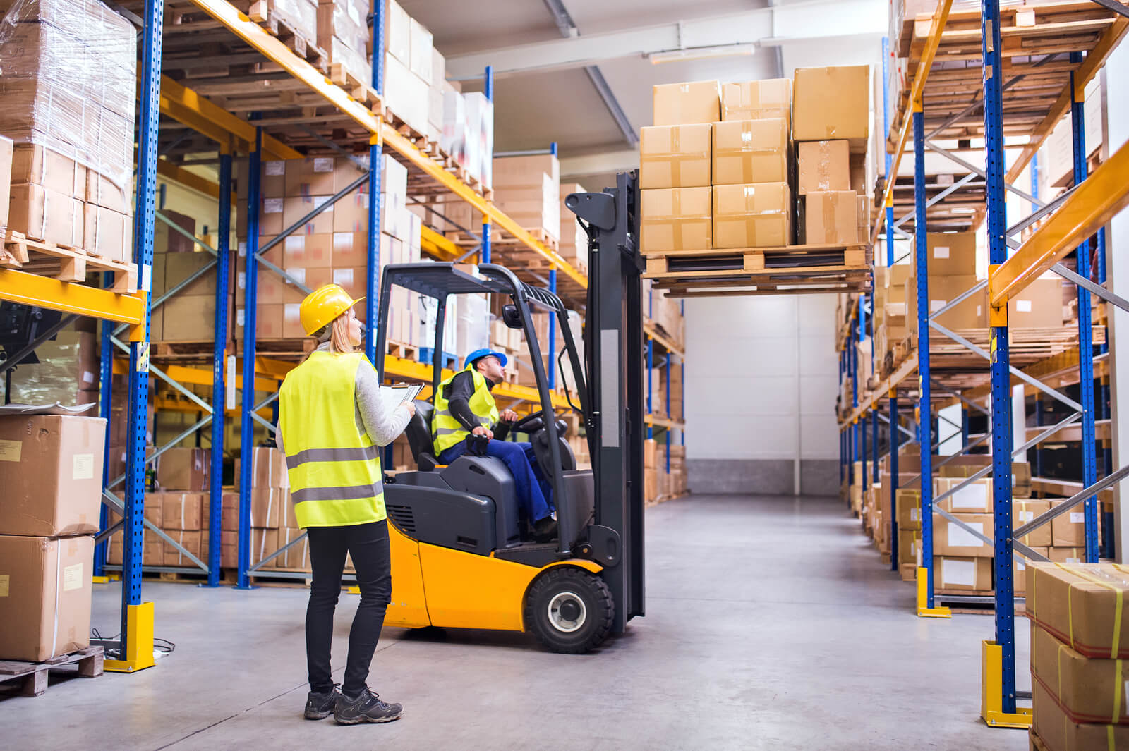 Warehouse workers with a forklift lifting products.